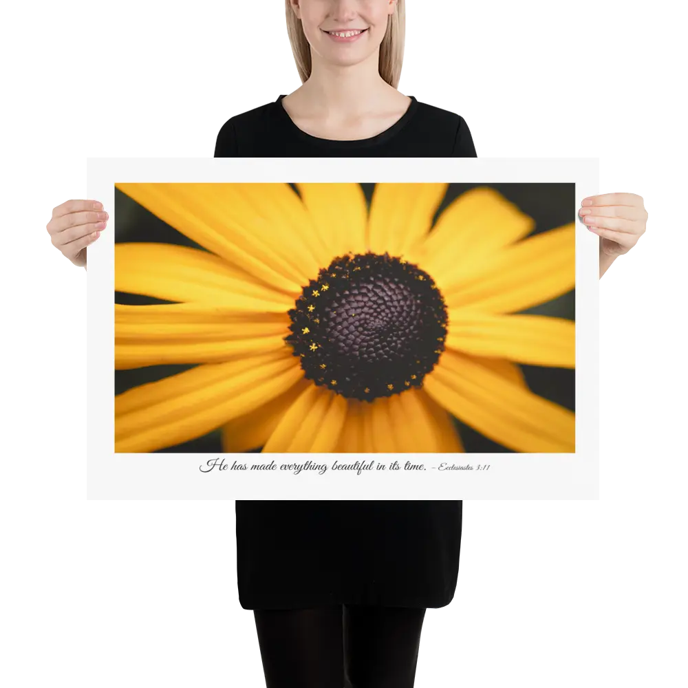 Person holding a large print of a yellow flower with a black center.
