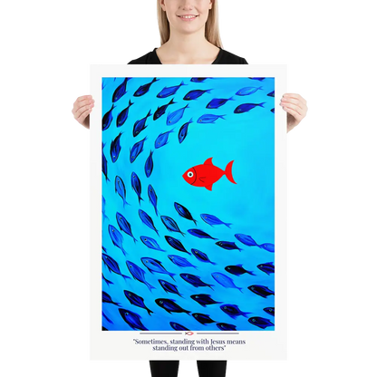 Person holding a poster with a red fish among blue fish and text on a white background