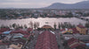 A video of the city of Kampot in Cambodia, there is a river and mountains in the background, traffic and houses with red roofs