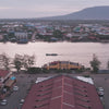 A video of the city of Kampot in Cambodia, there is a river and mountains in the background, traffic and houses with red roofs