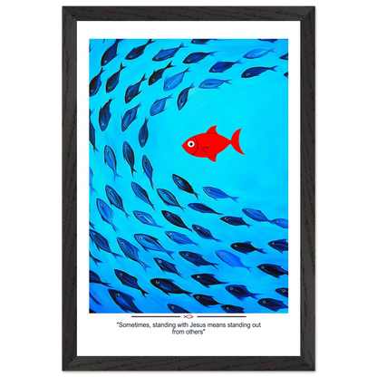 Framed Christian wall art featuring a red fish swimming in water with blue fish, and the text 'Sometimes standing with Jesus means standing out from others' as a quote.